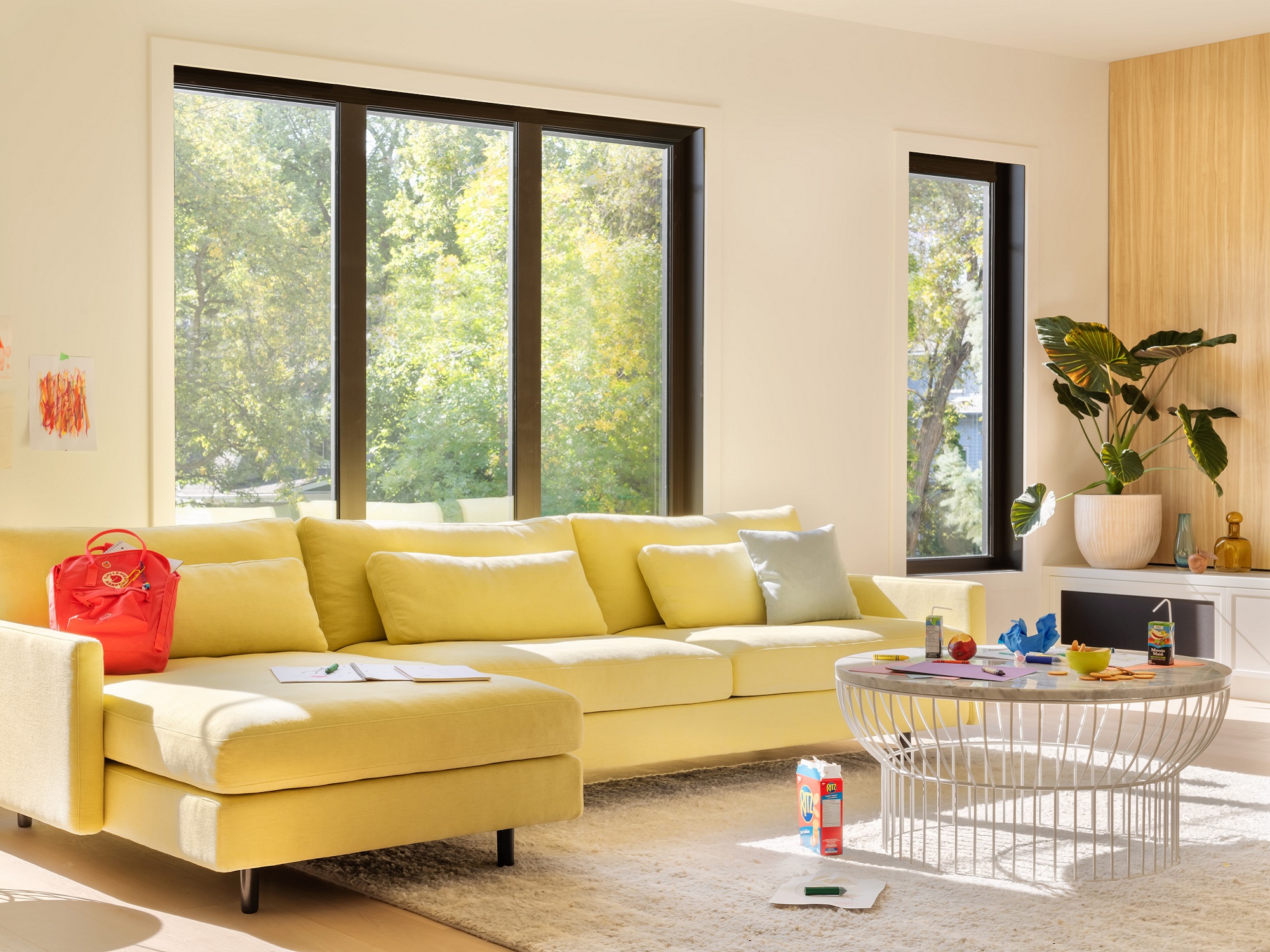 Round white wire coffee table with yellow sectional in bright living room