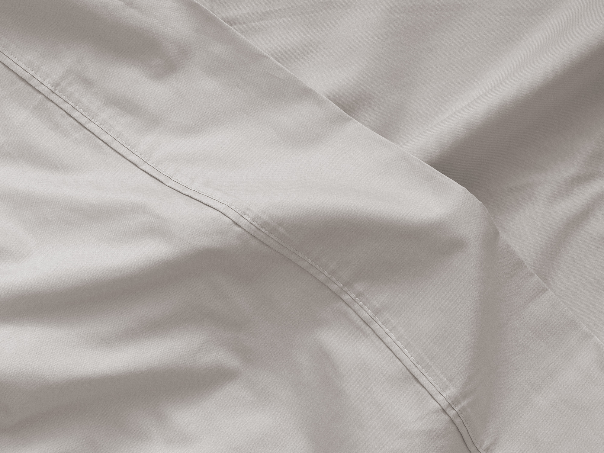 Detail view of top fold of organic cotton bed sheets in off white