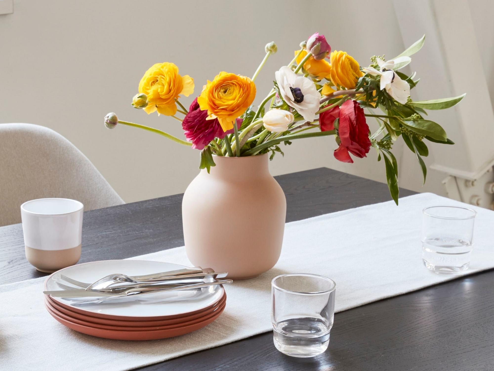 Blush ceramic flower vase with dishes and runner on dining room table