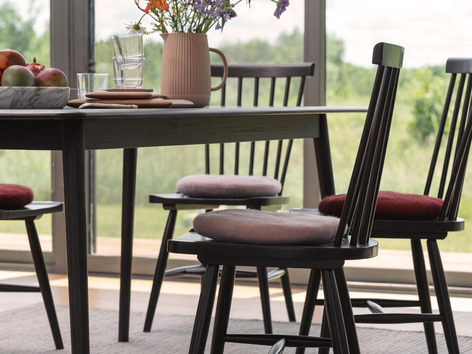 Red and pink seat cushions on black dining chairs around dining room table