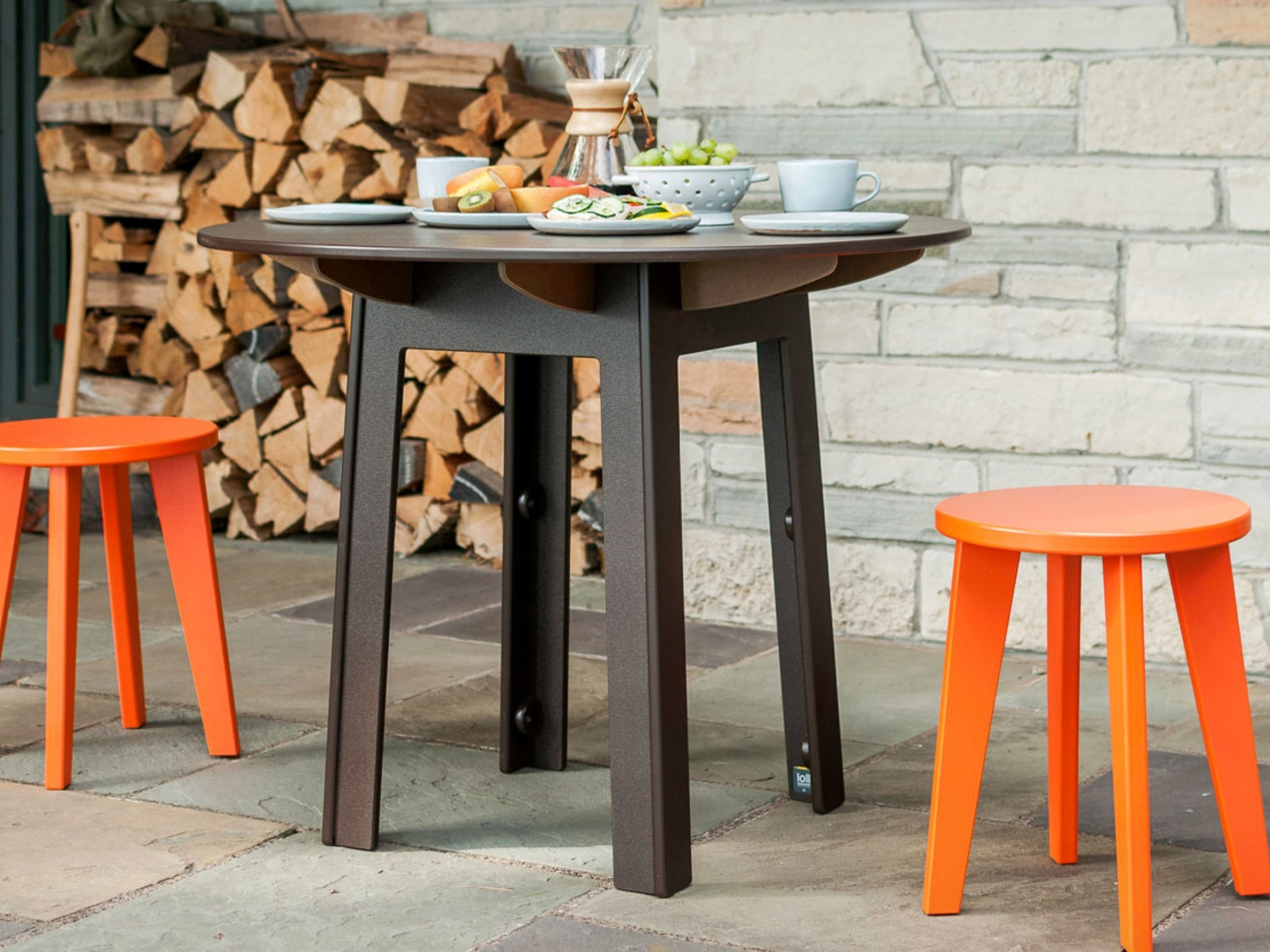 Outdoor dinette table and orange bar stools on a stone patio