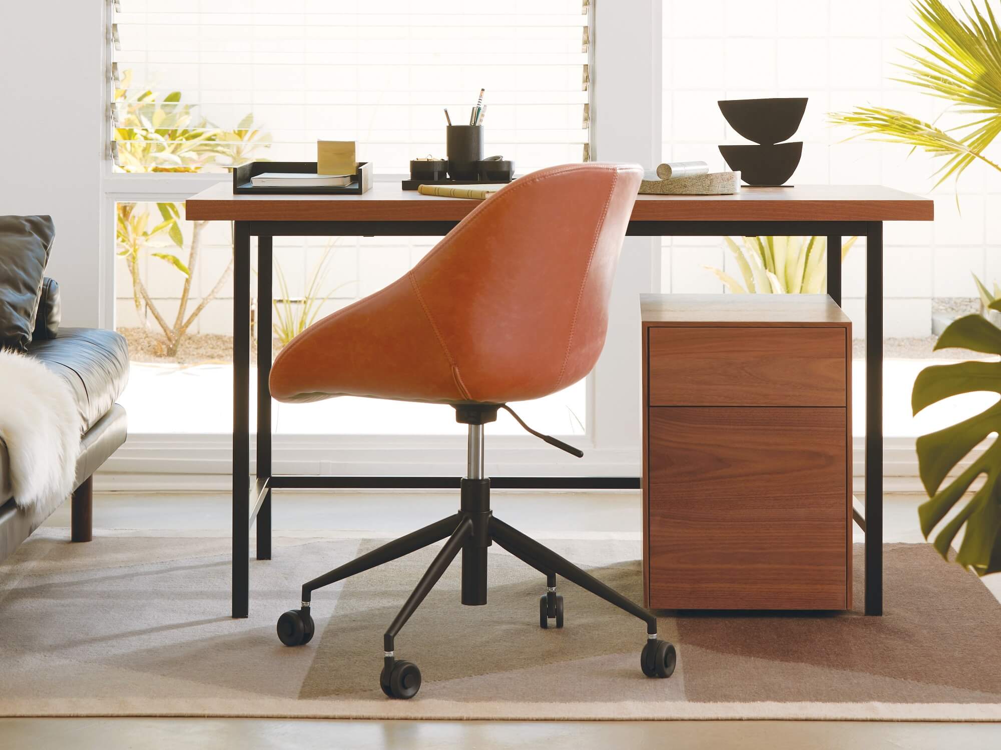 Walnut file cabinet beneath desk and leather office chair in bright living room