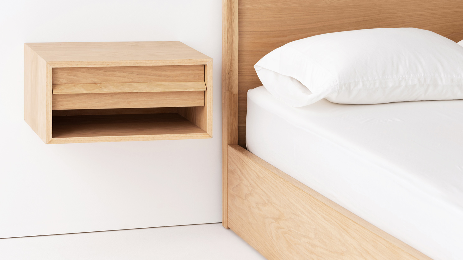 The Marcel open shelf floating nightstand in oak beside its matching bed