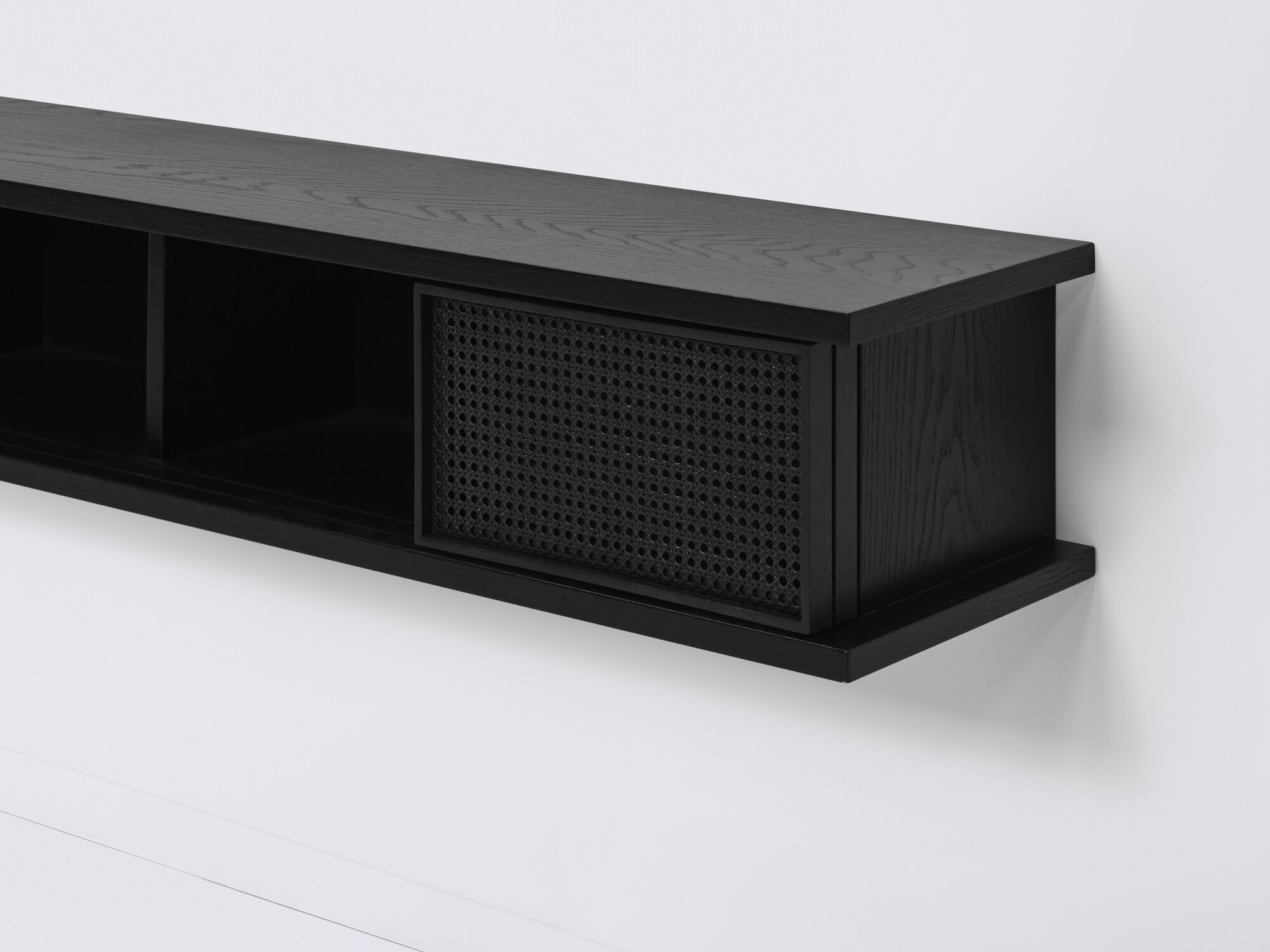 Long black floating shelf with black cane doors open detail view