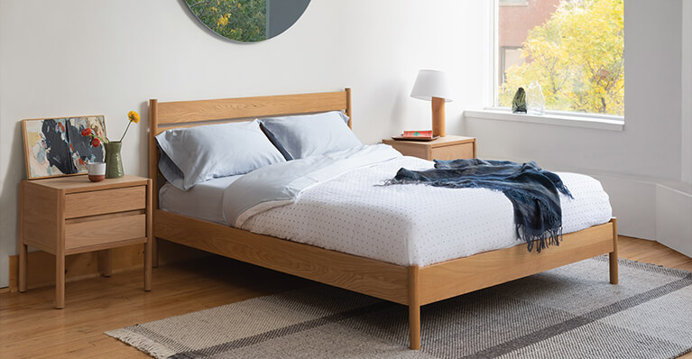 Oak bed frame is shown in a small bedroom. Link to beds category