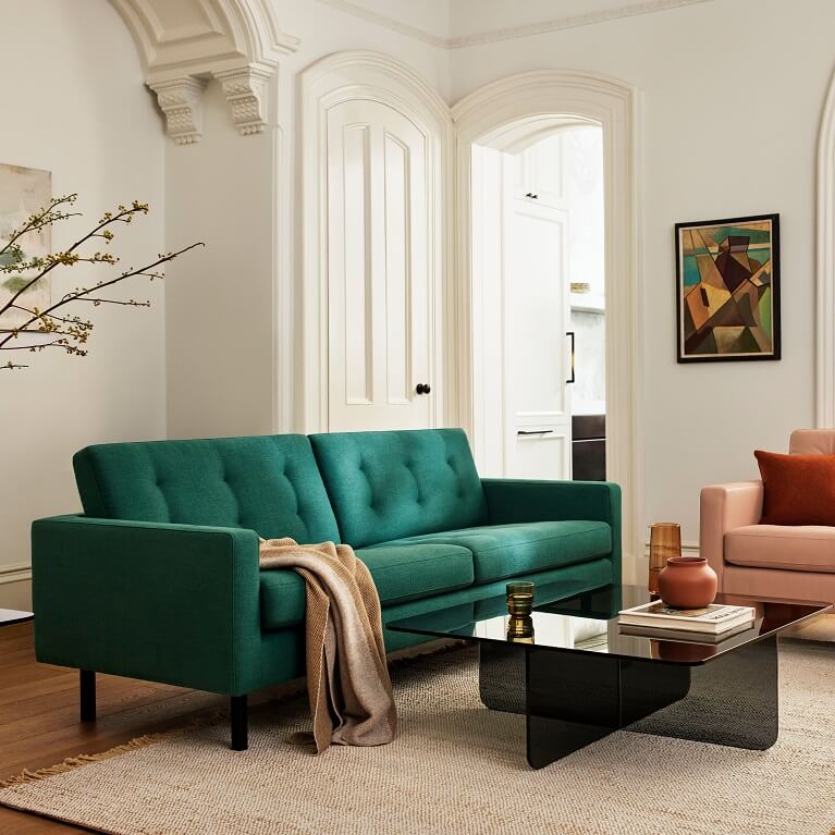 Green sofa and pink chair sit in a living room. Link to seating category