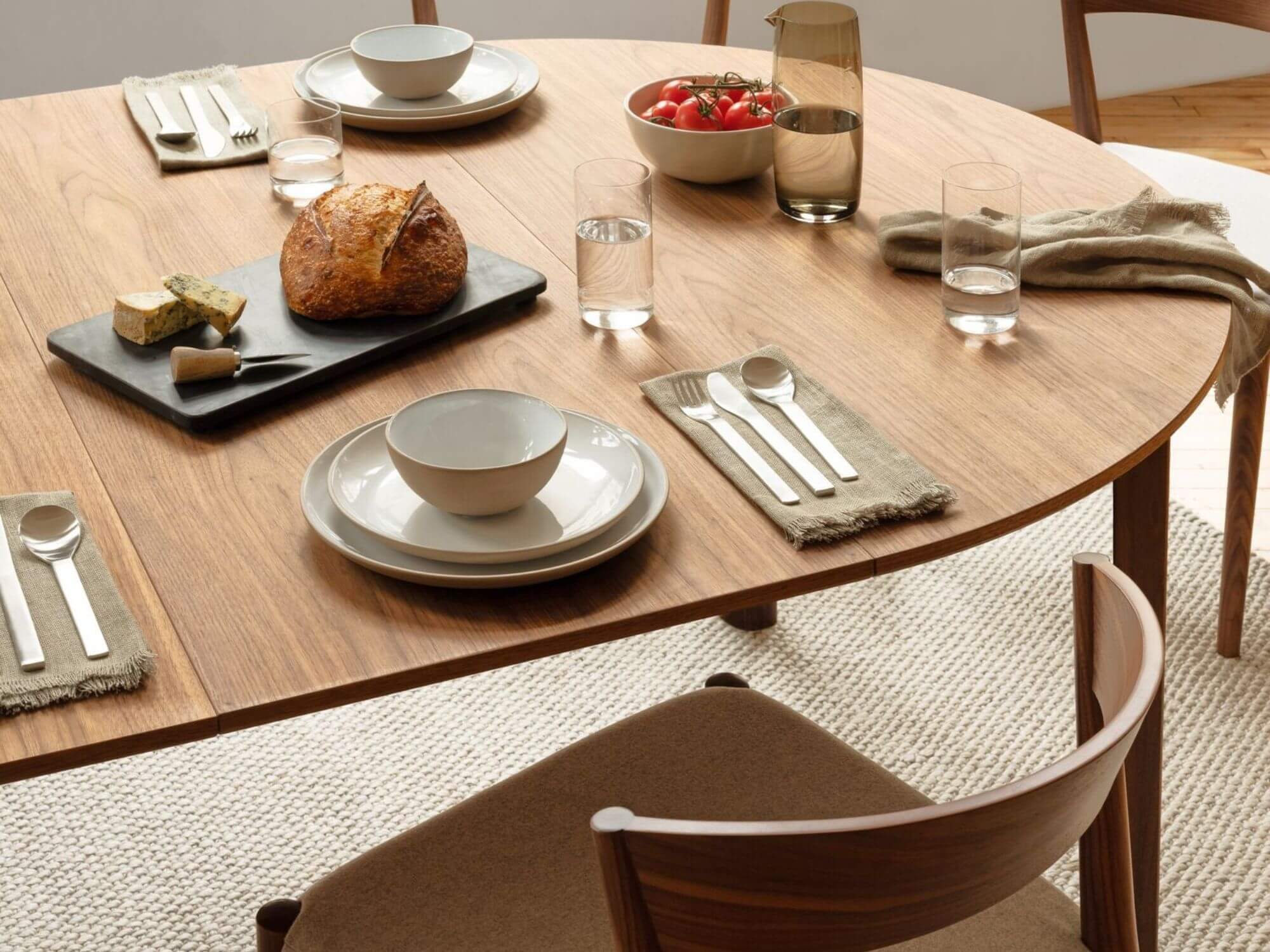 Modern flatware set with dishes, napkins, and bread on a long dining room table