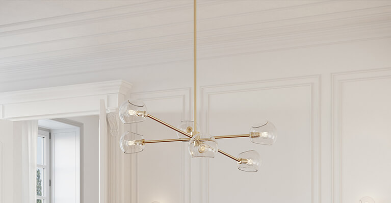 A large gold pendant light hangs in front of a white wall. Link to kuzco lighting