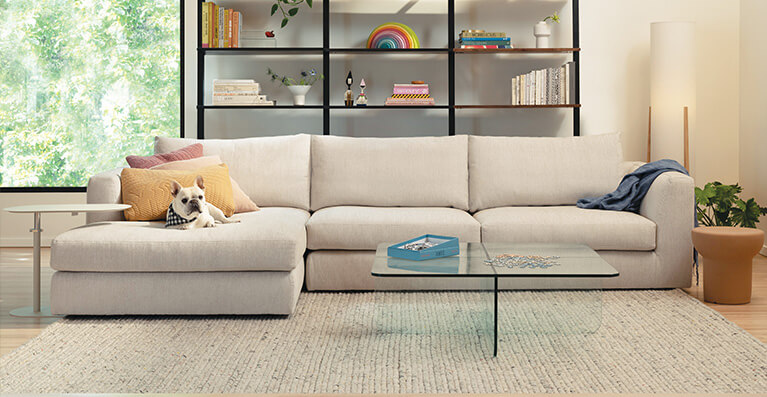 Un grand sectionnel en tissu beige clair est exposé dans un salon. Lien vers la catégorie canapes-modulaires