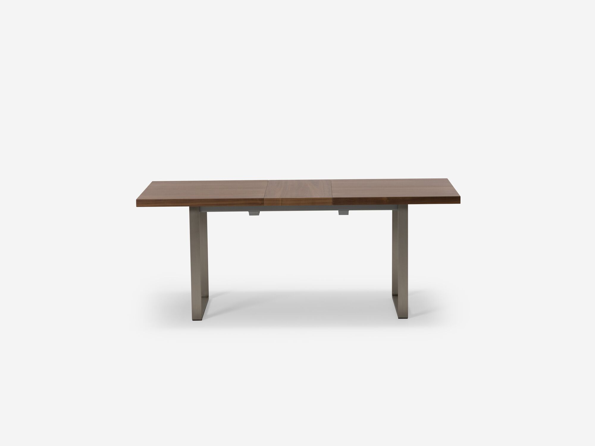 Expandable dining table with stainless steel legs and walnut top with one leaf side view