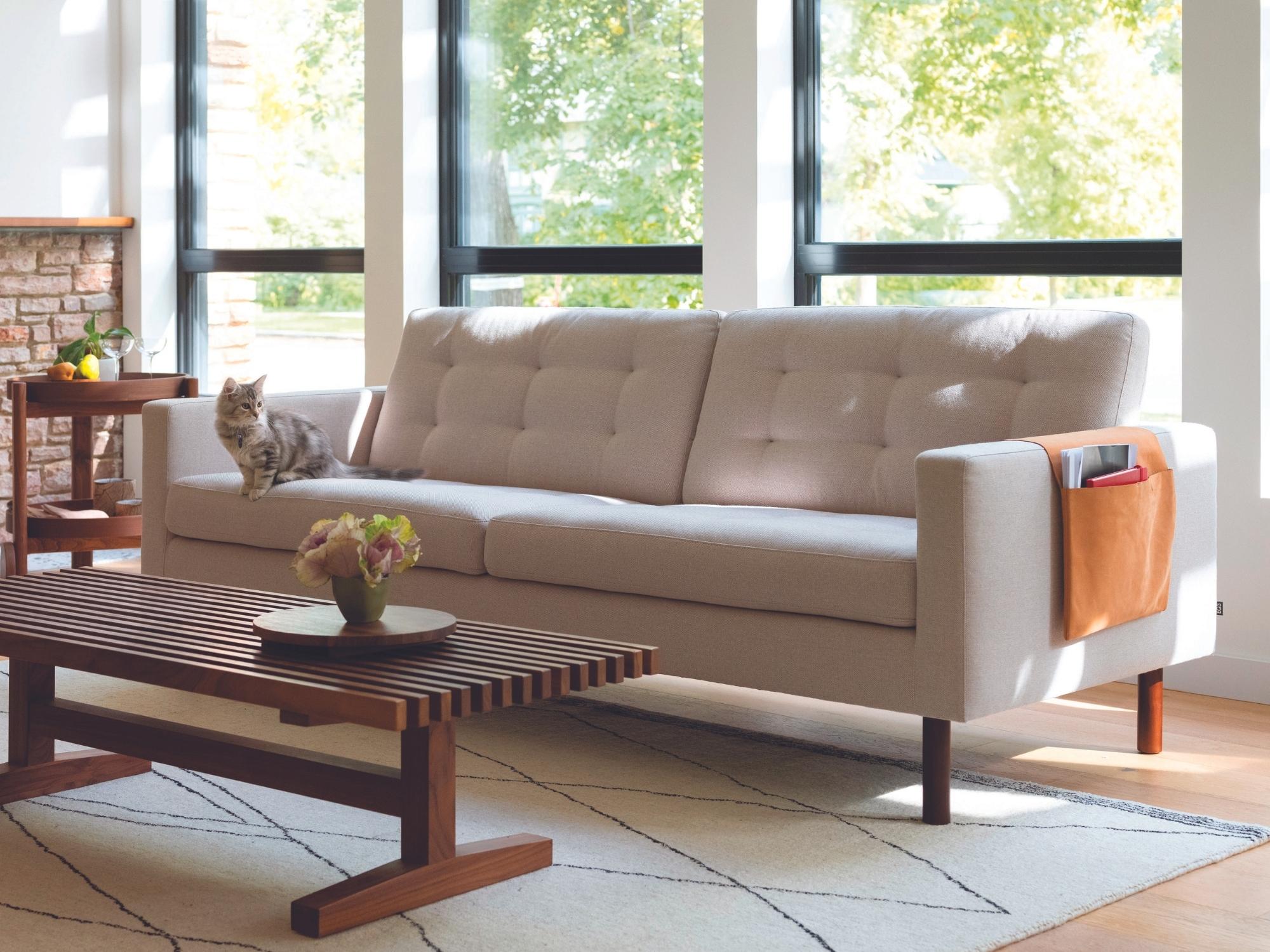 Tufted beige sofa with slatted walnut coffee table in mid century room