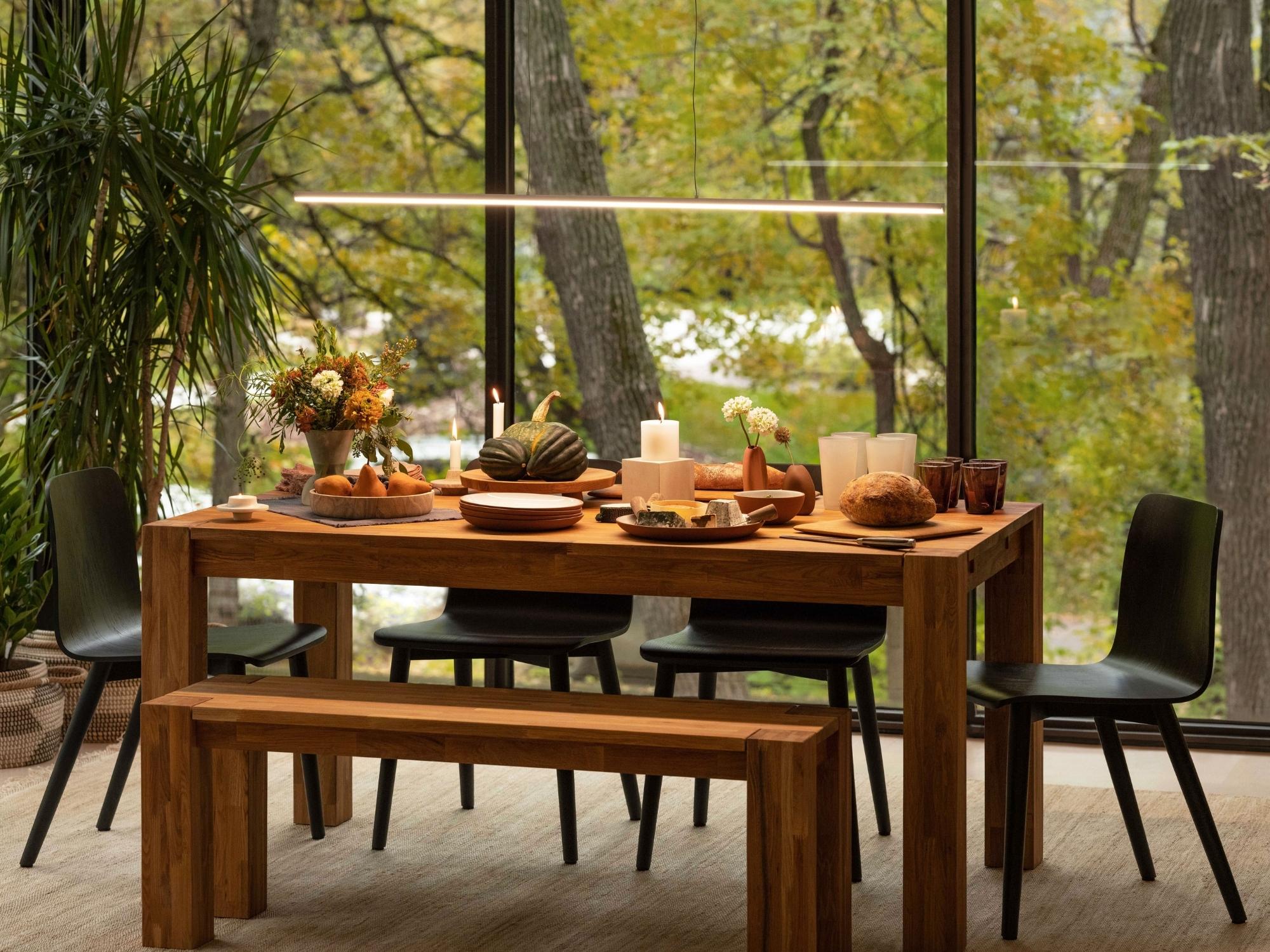 Modern slim line pendant light over wood dining table with chairs