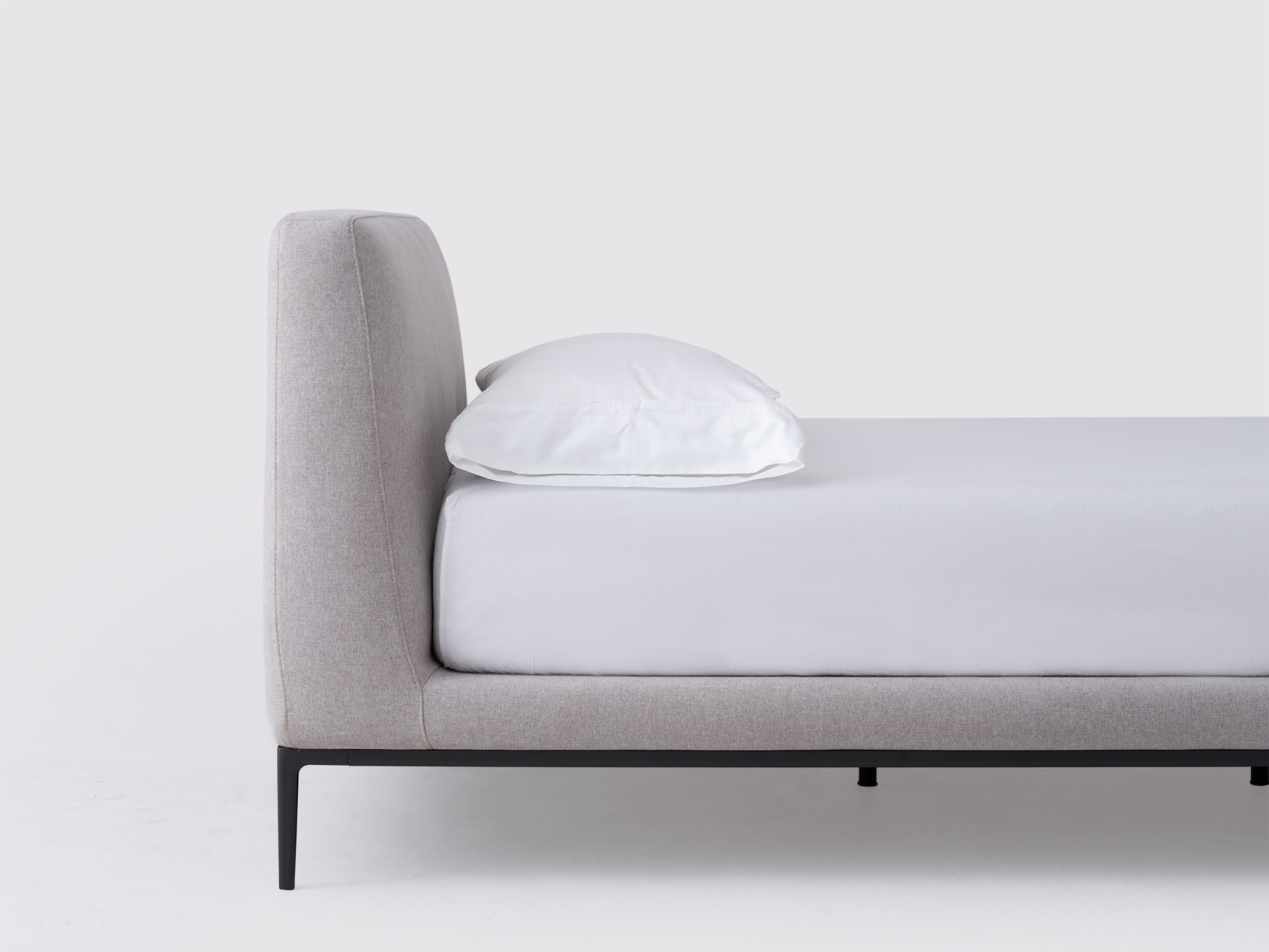 Detail view of the Oma upholstered bed in gray fabric