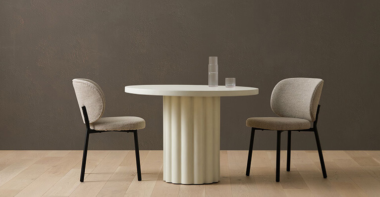 Two white dining chairs and a round dining table are displayed in a studio setting. Link to sale page