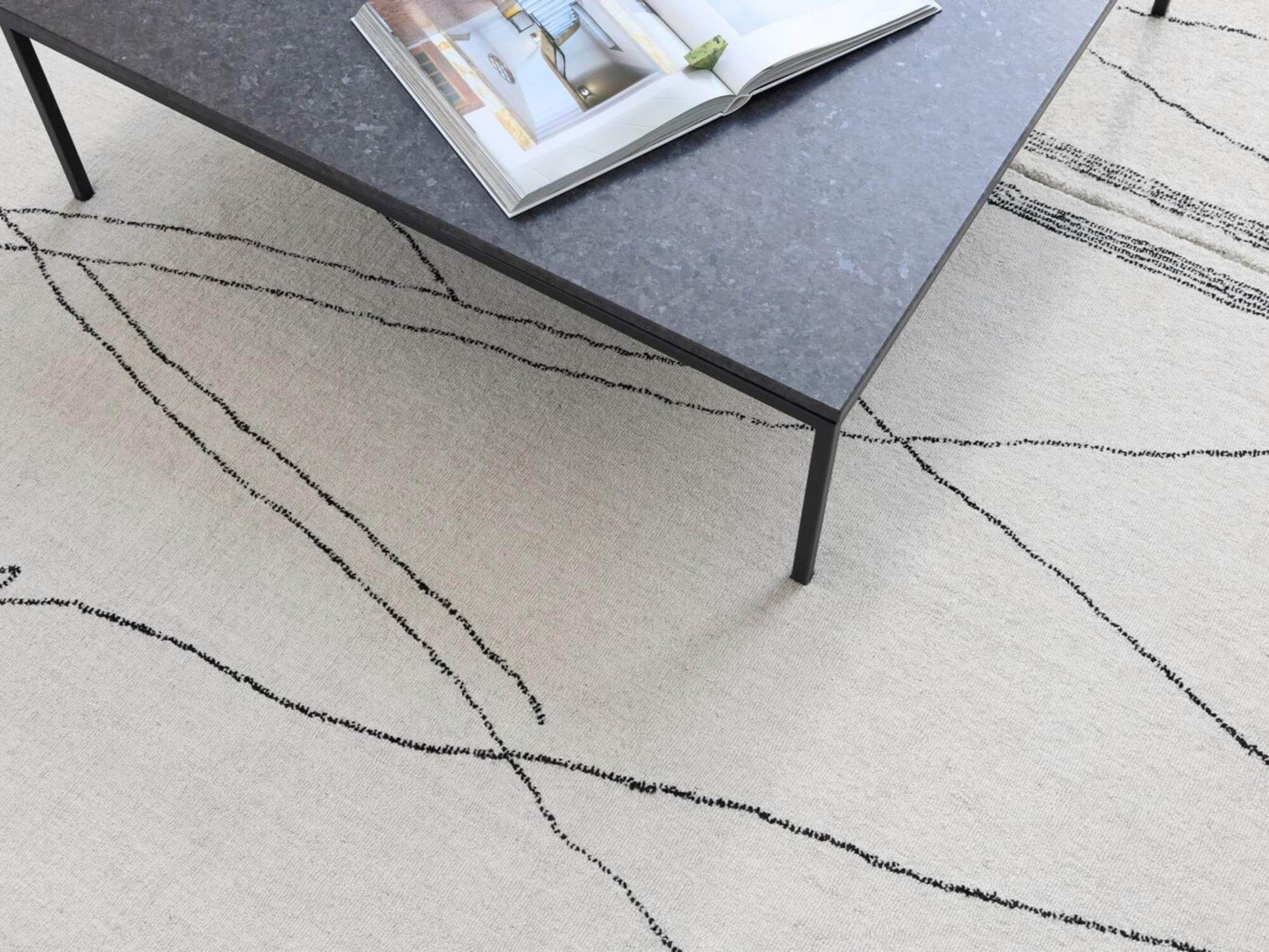 Beige rug with black diamond stripes and a walnut bar cart wheel on it