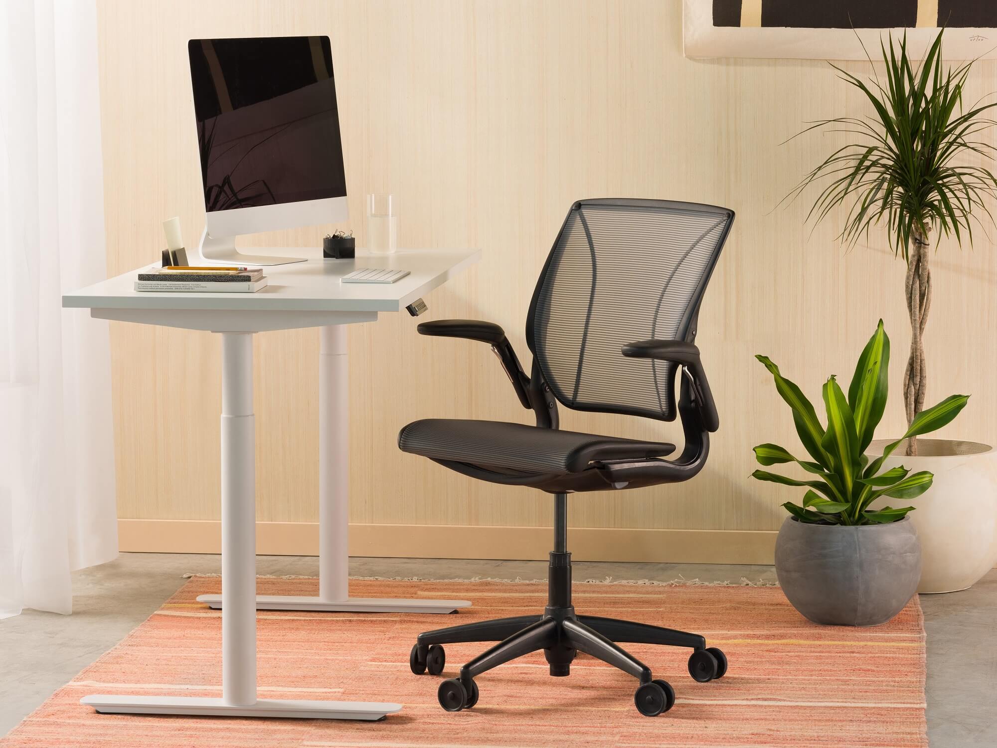 White standing desk with black computer chair and red rug