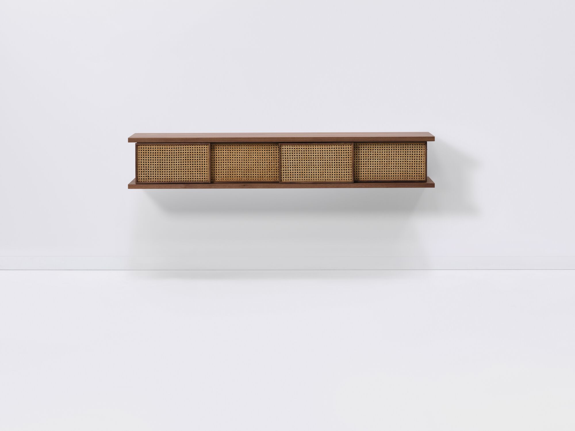 Front view of medium walnut floating shelf with natural cane doors