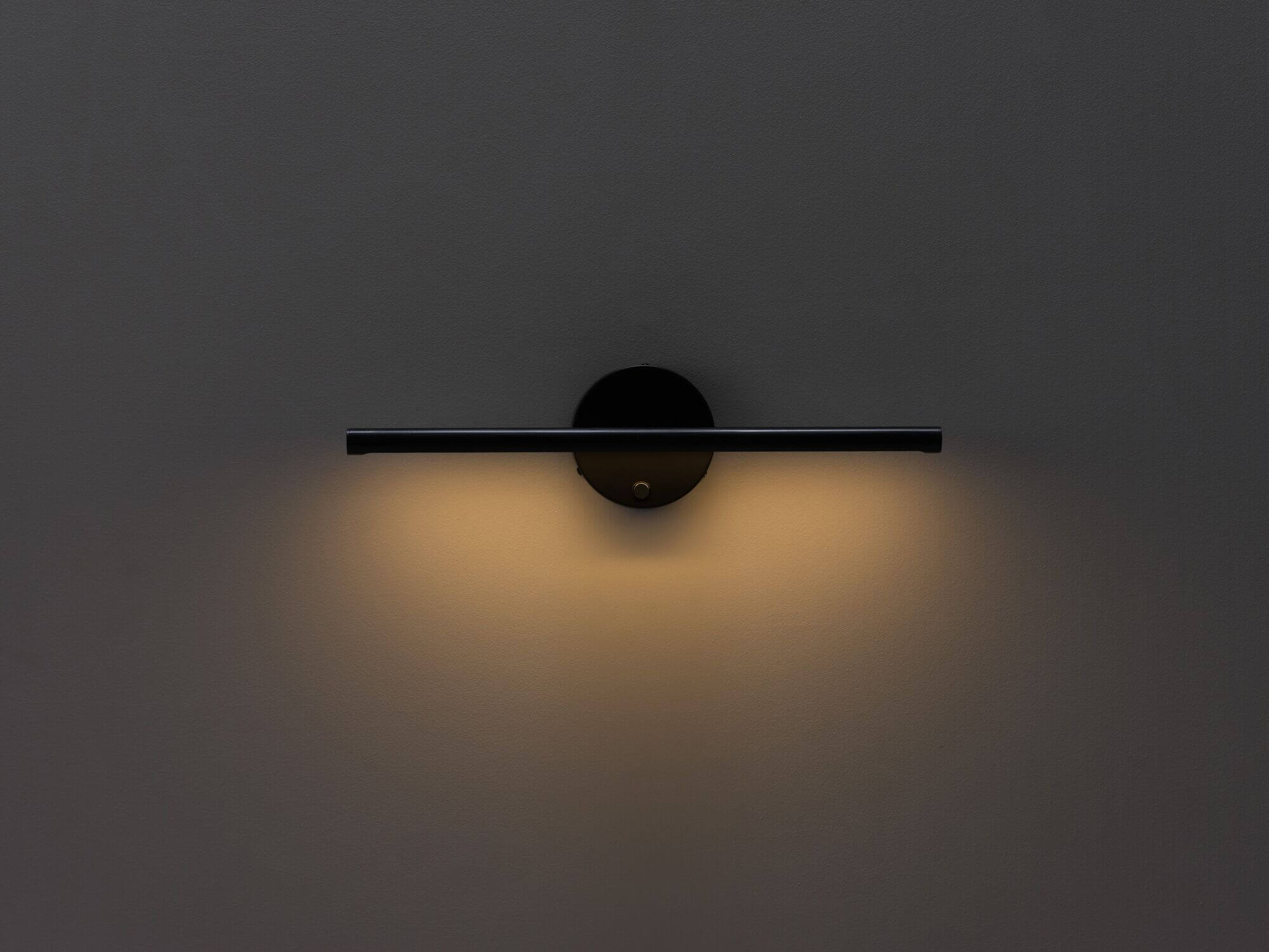 Black slim wall lamp with light on low front view