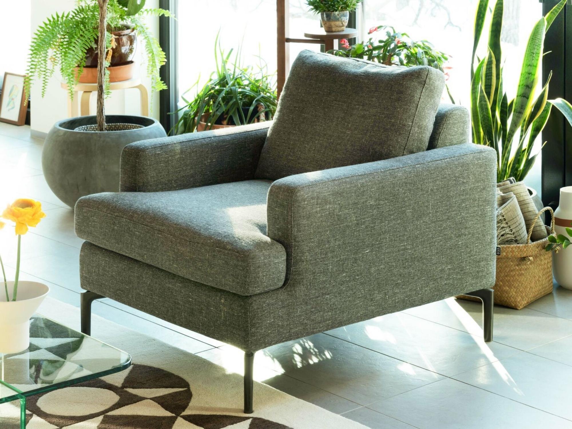 Green upholstered armchair surrounded by potted plants