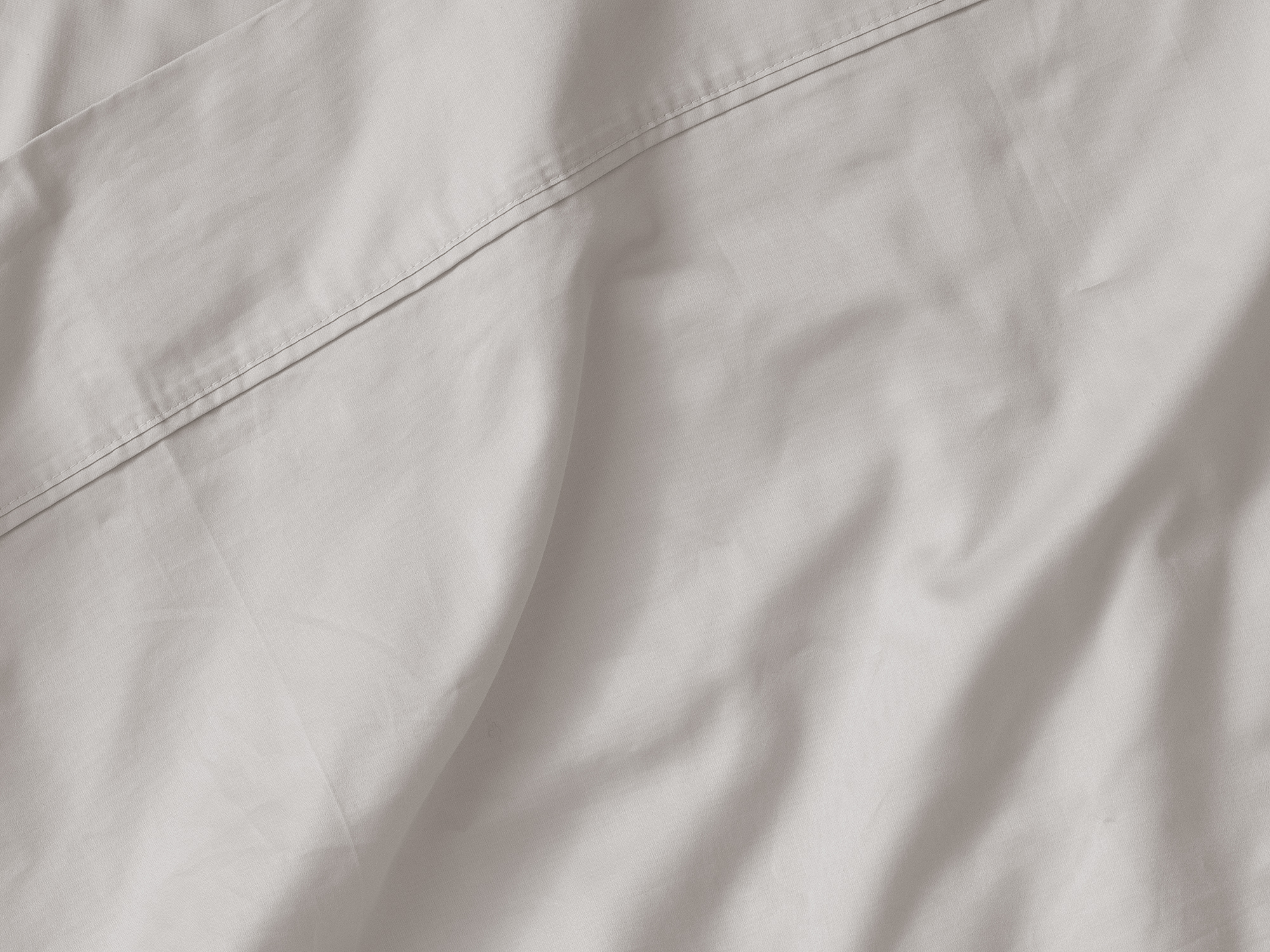 Detail view of organic cotton bed sheets in off white