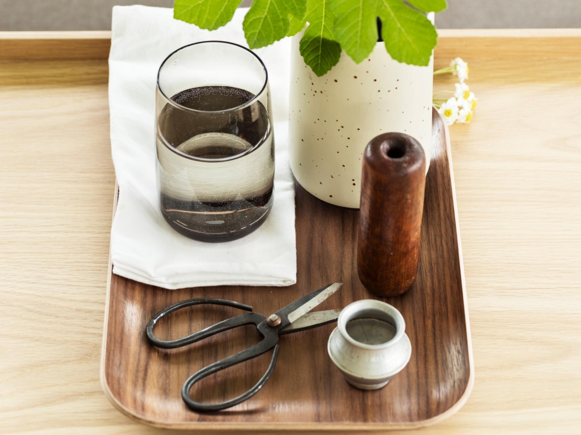 Grey glass highball with flower vase on walnut serving tray