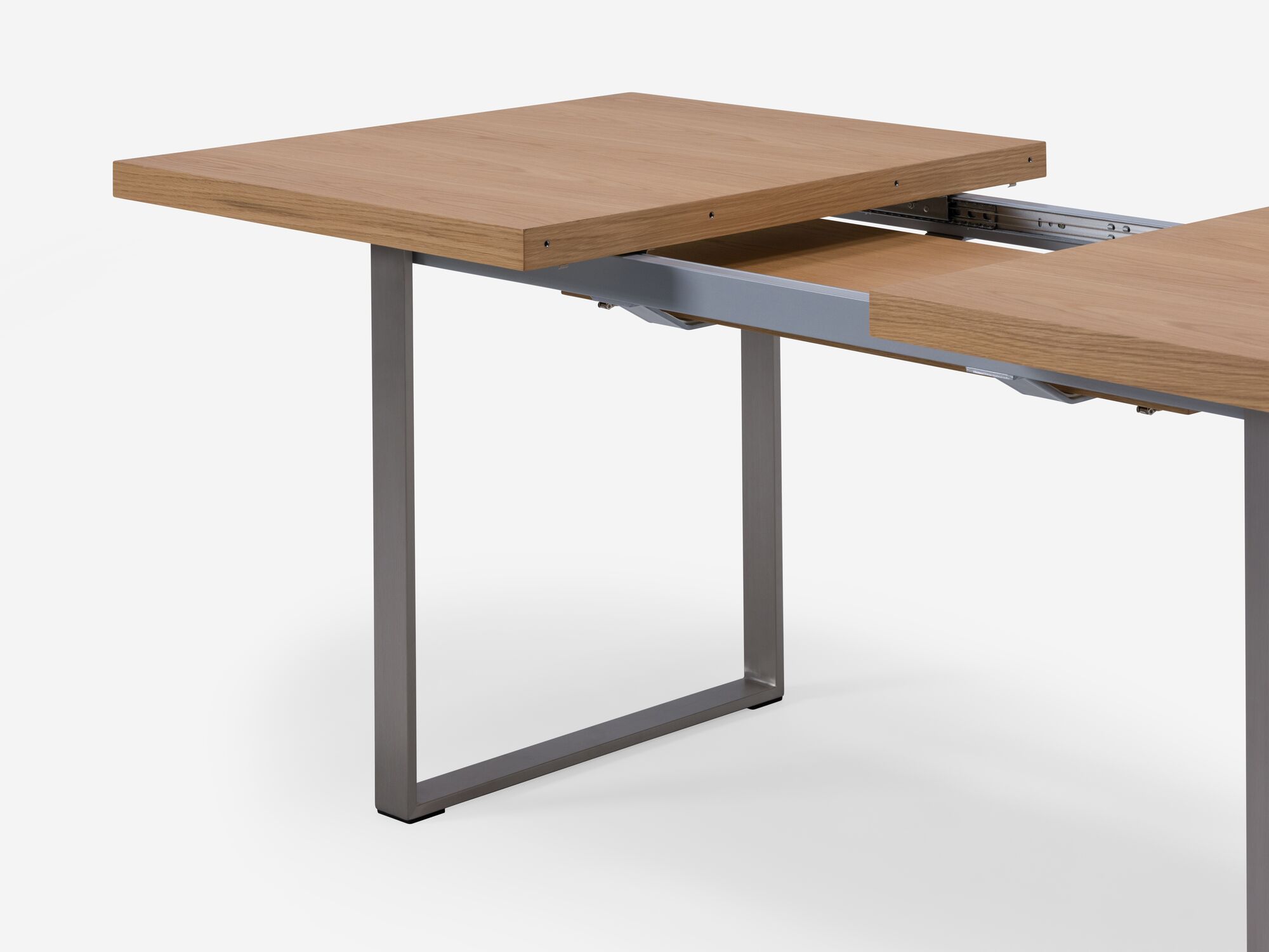 Detail view of expandable dining table with stainless steel legs and oak top