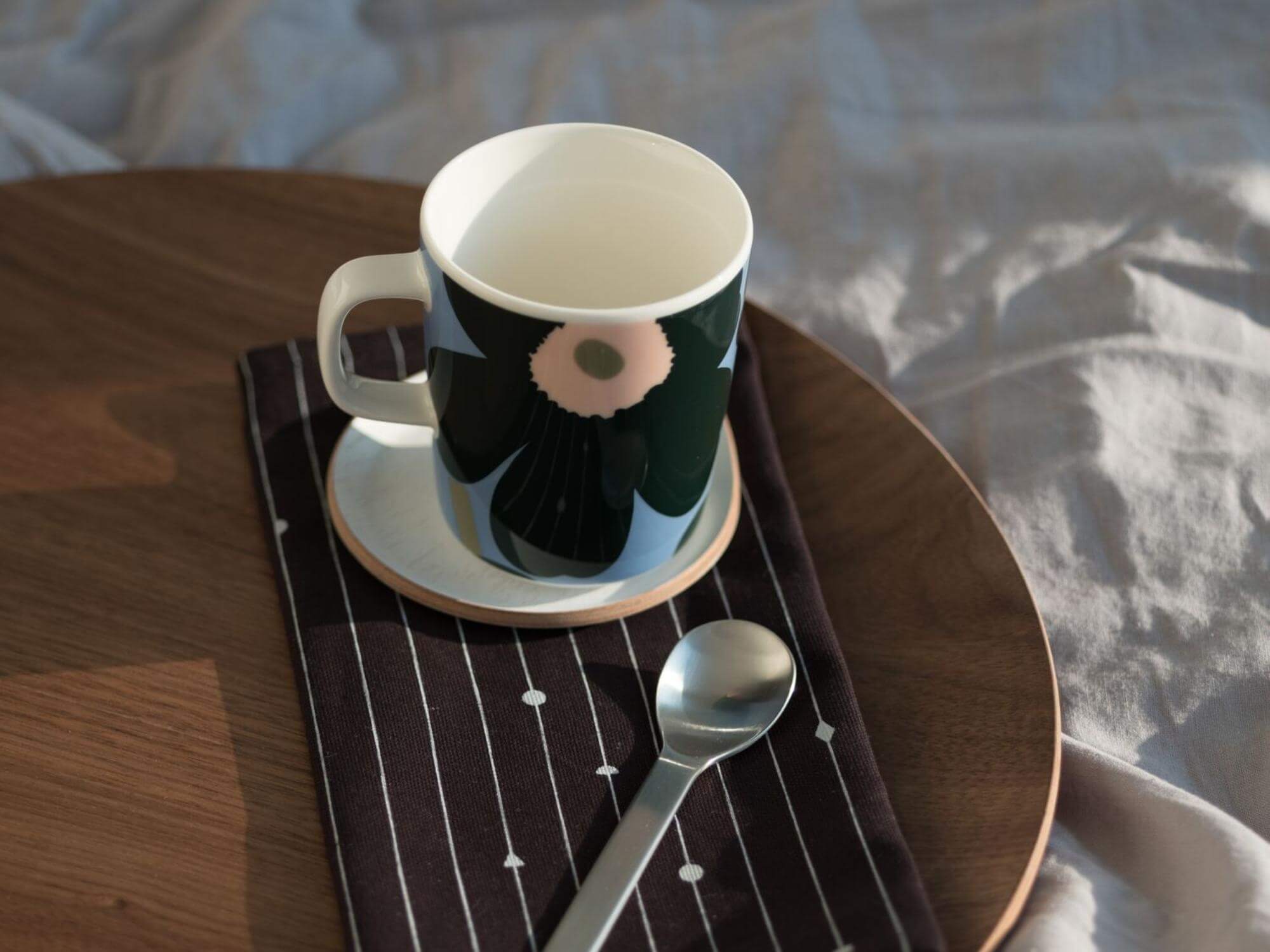 White coaster under floral mug with blue napkin on serving tray