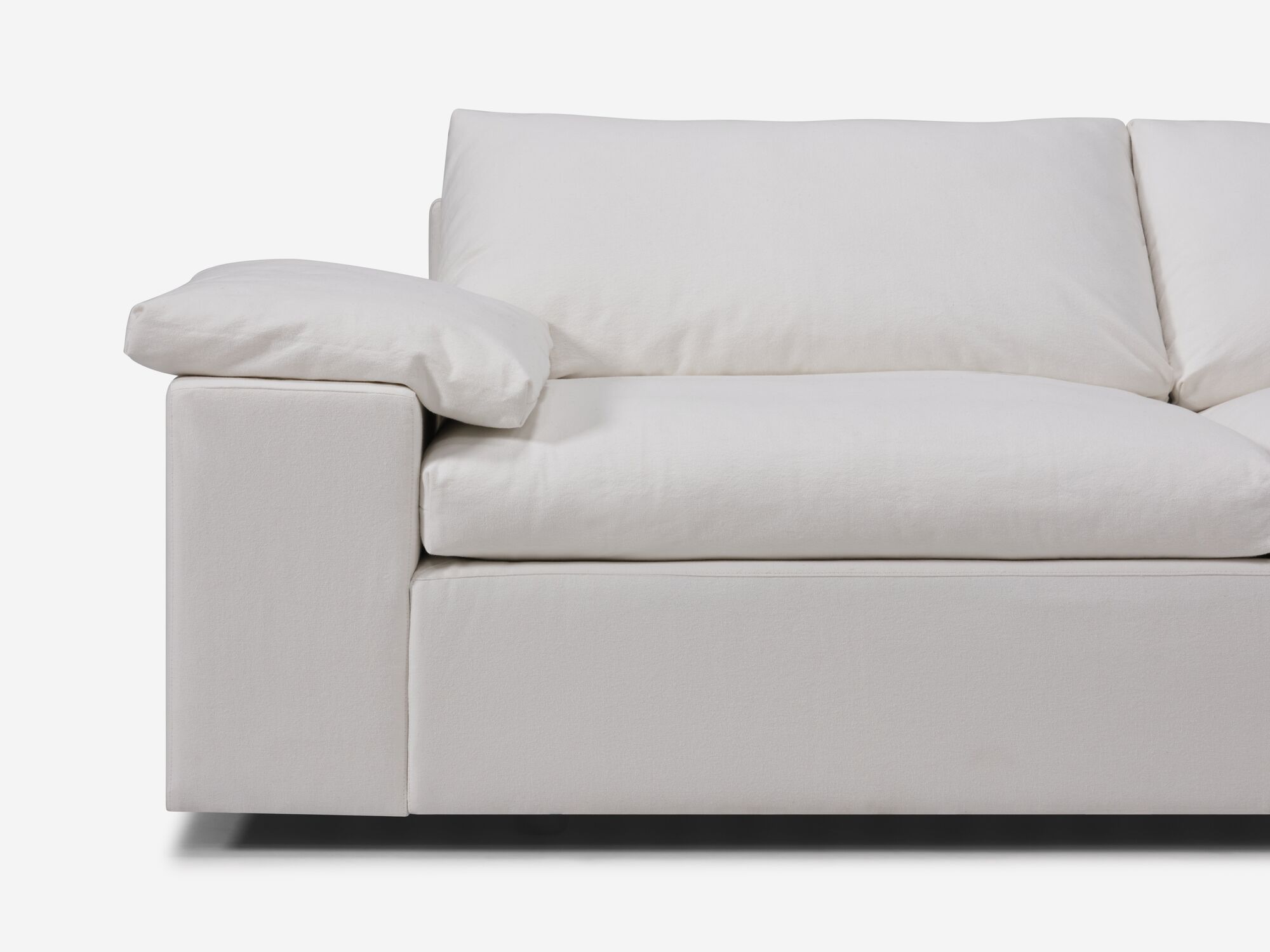 Detail view of white sectional sofa with right hand chaise, pillow and wide arms