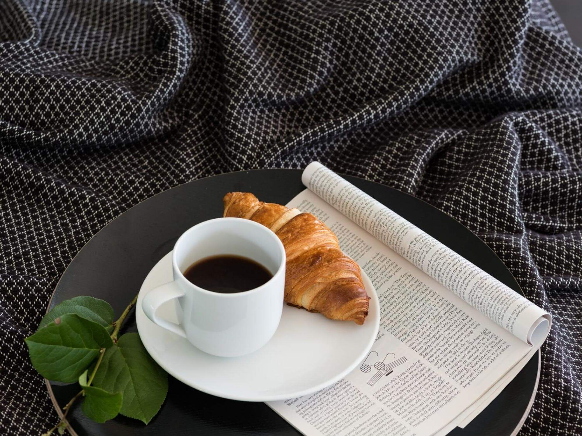 Dark grey throw blanket with serving tray and coffee cup on it