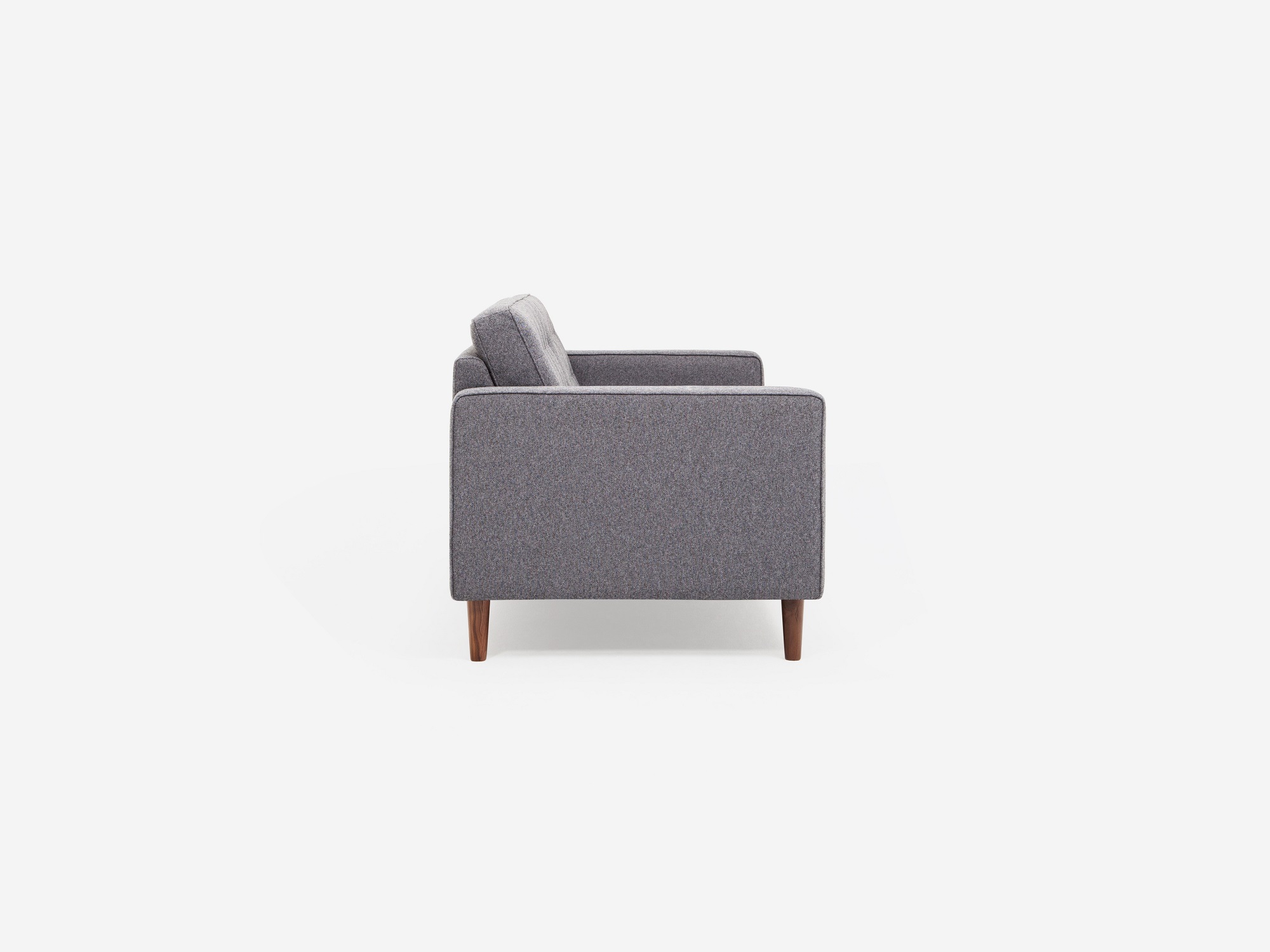 Side view of grey tufted apartment sofa with black ash legs