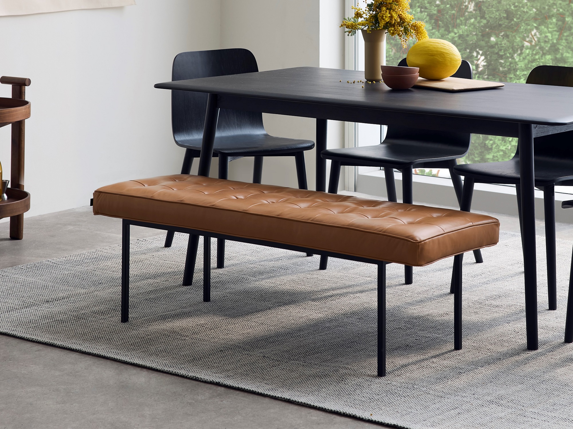 Brown leather dining bench at black oak dining table