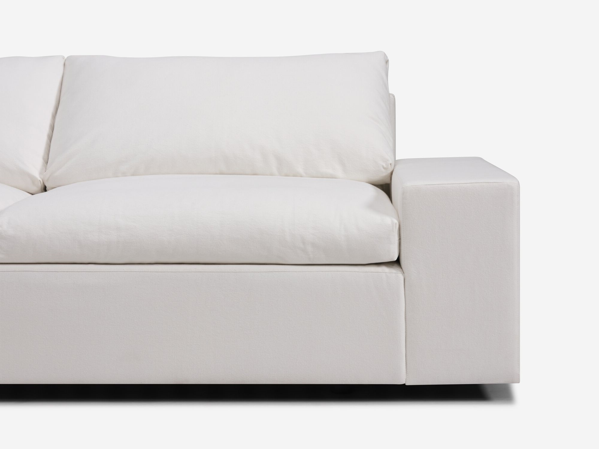 Detail view of white sectional sofa with left hand chaise and wide arms