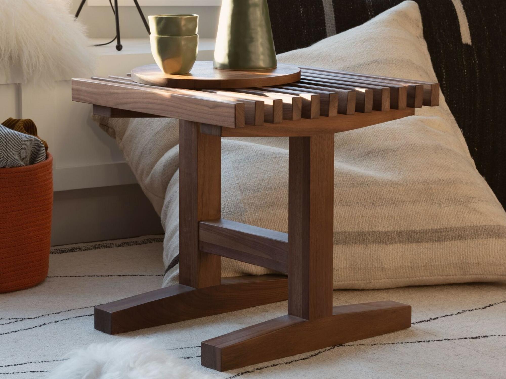 Slatted walnut end table with beige and black throw pillows