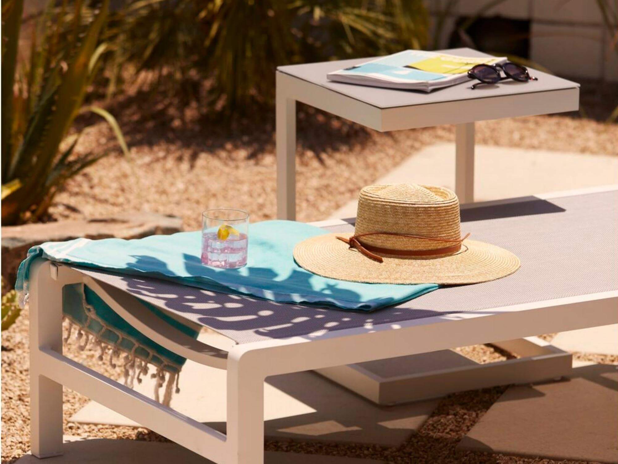 Gray and white outdoor side table with chaise on a pool deck