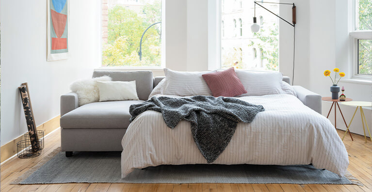 Grey fabric sleeper sectional is shown extended in a living room. Link to sleeper sofa