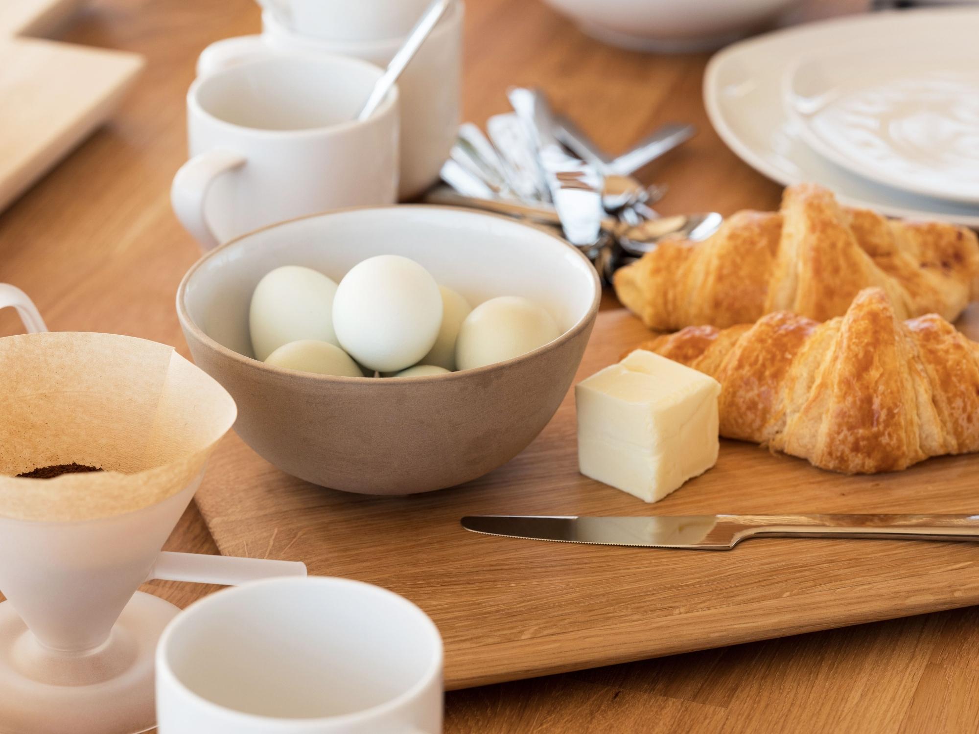 Grey and white stone bowl with eggs in it, on crowded dining table