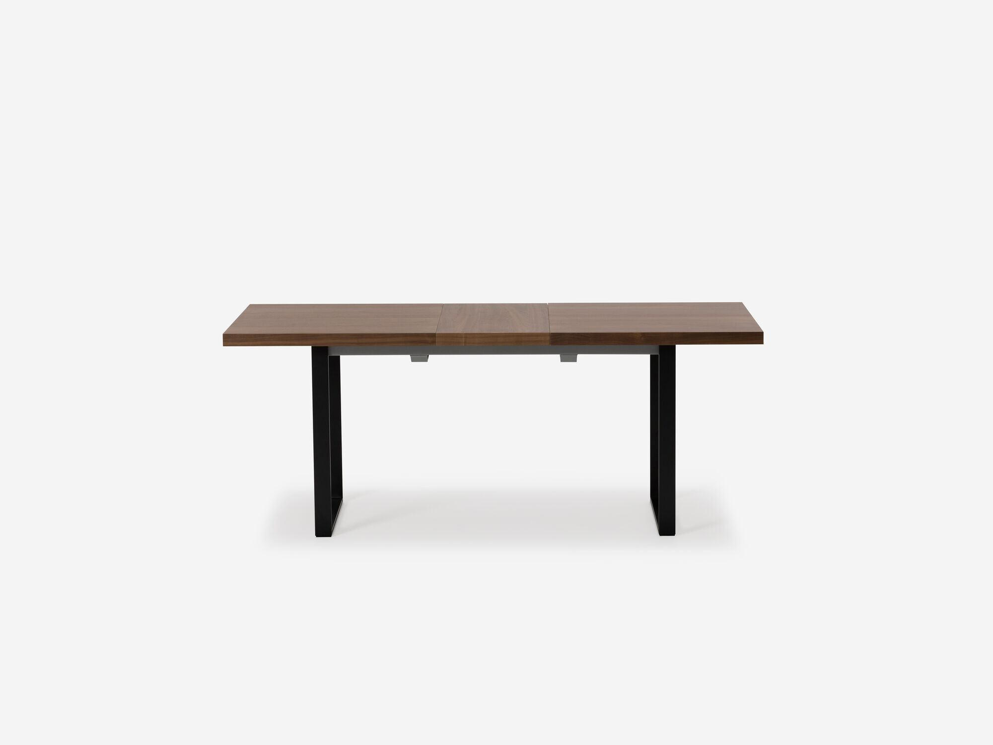 Side view of expandable dining table with black legs and walnut top with one leaf