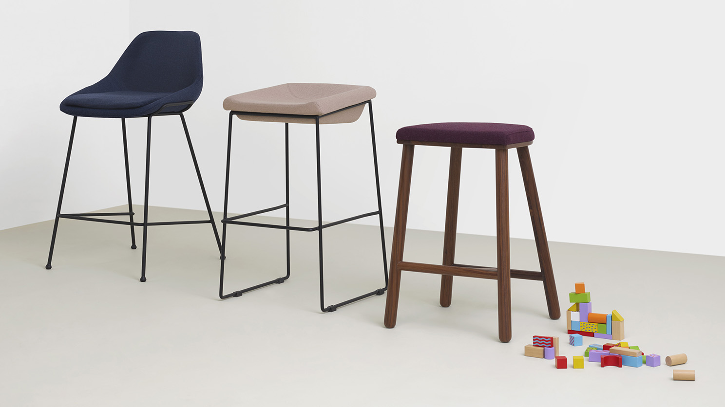 The Nixon bar stool with back beside two other bar stools and a pile of lego in a white room