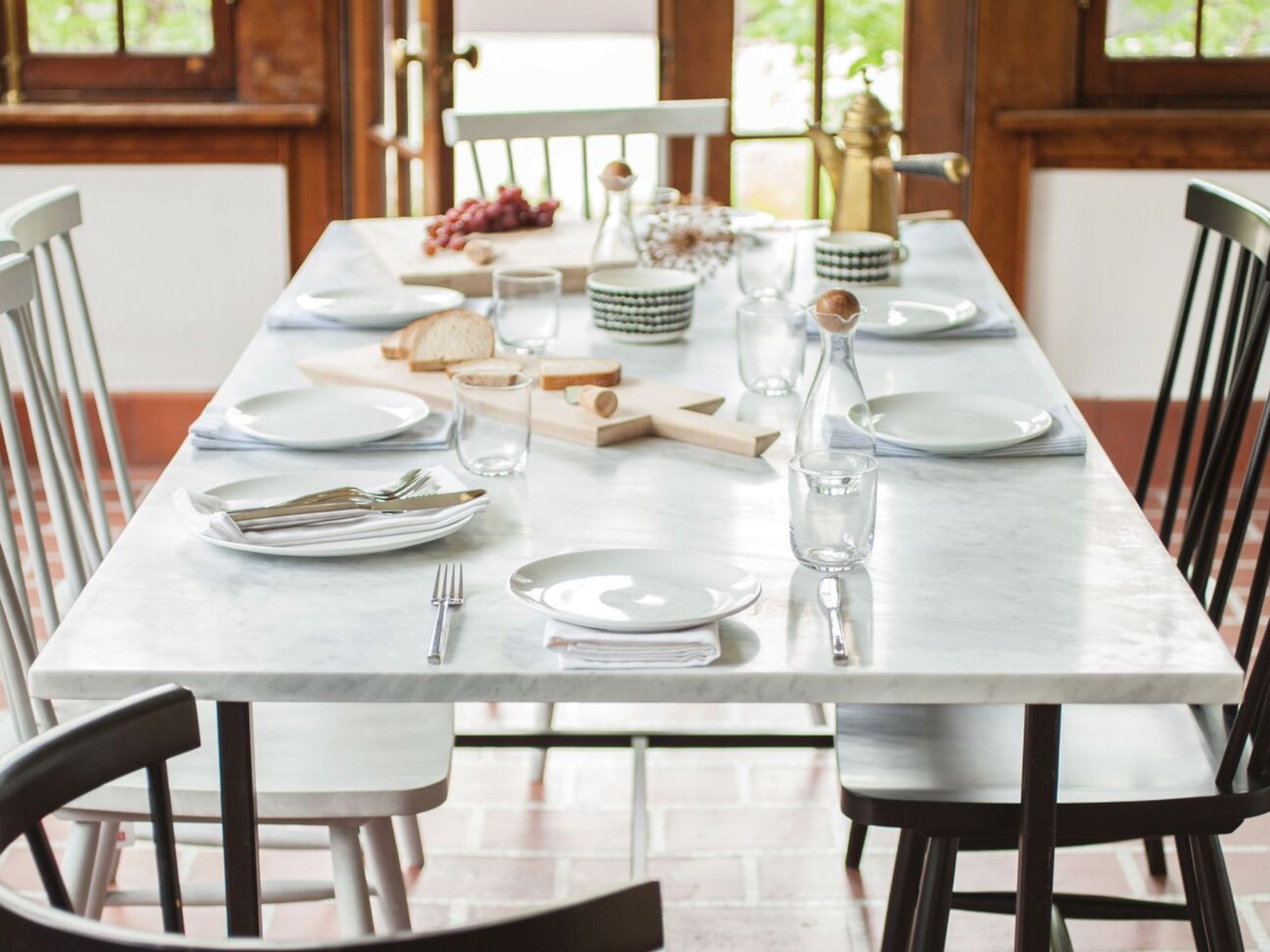 Stainless steel flatware set with white dishes on marble table