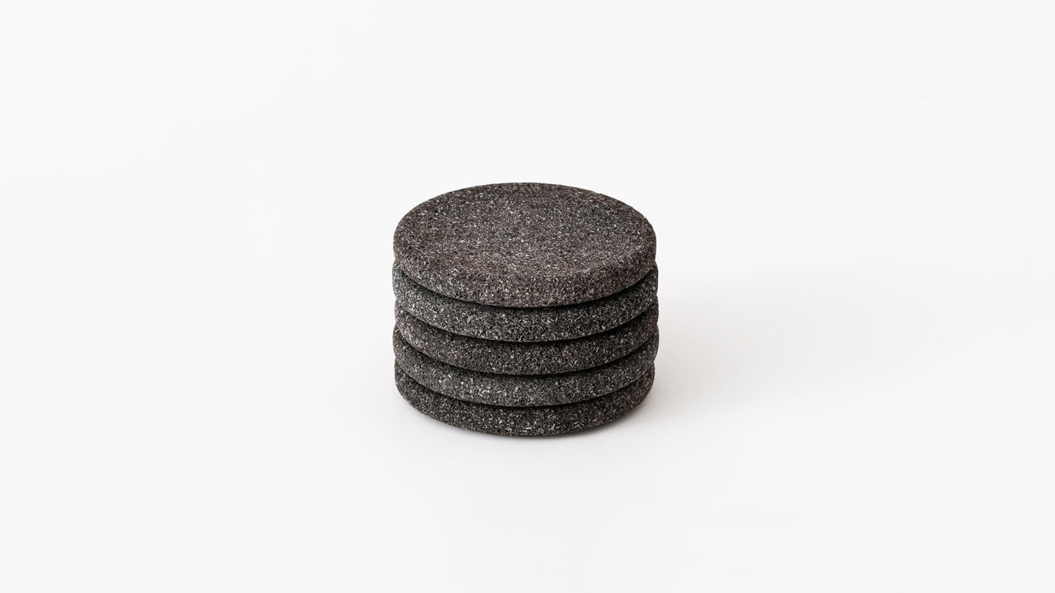 Side view of a stack of four coasters in lava stone