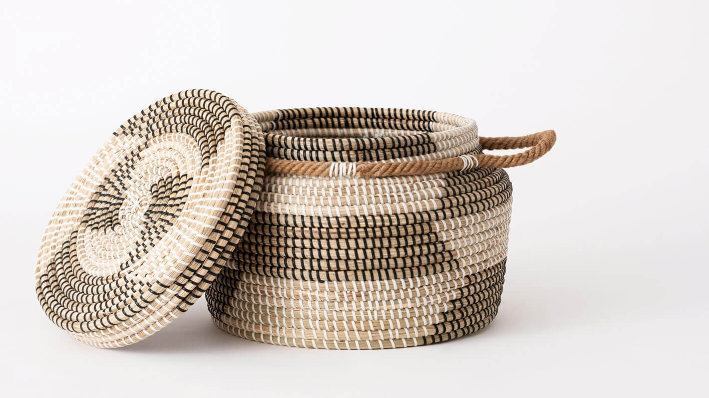 Side view of medium handwoven black and beige basket with lid off