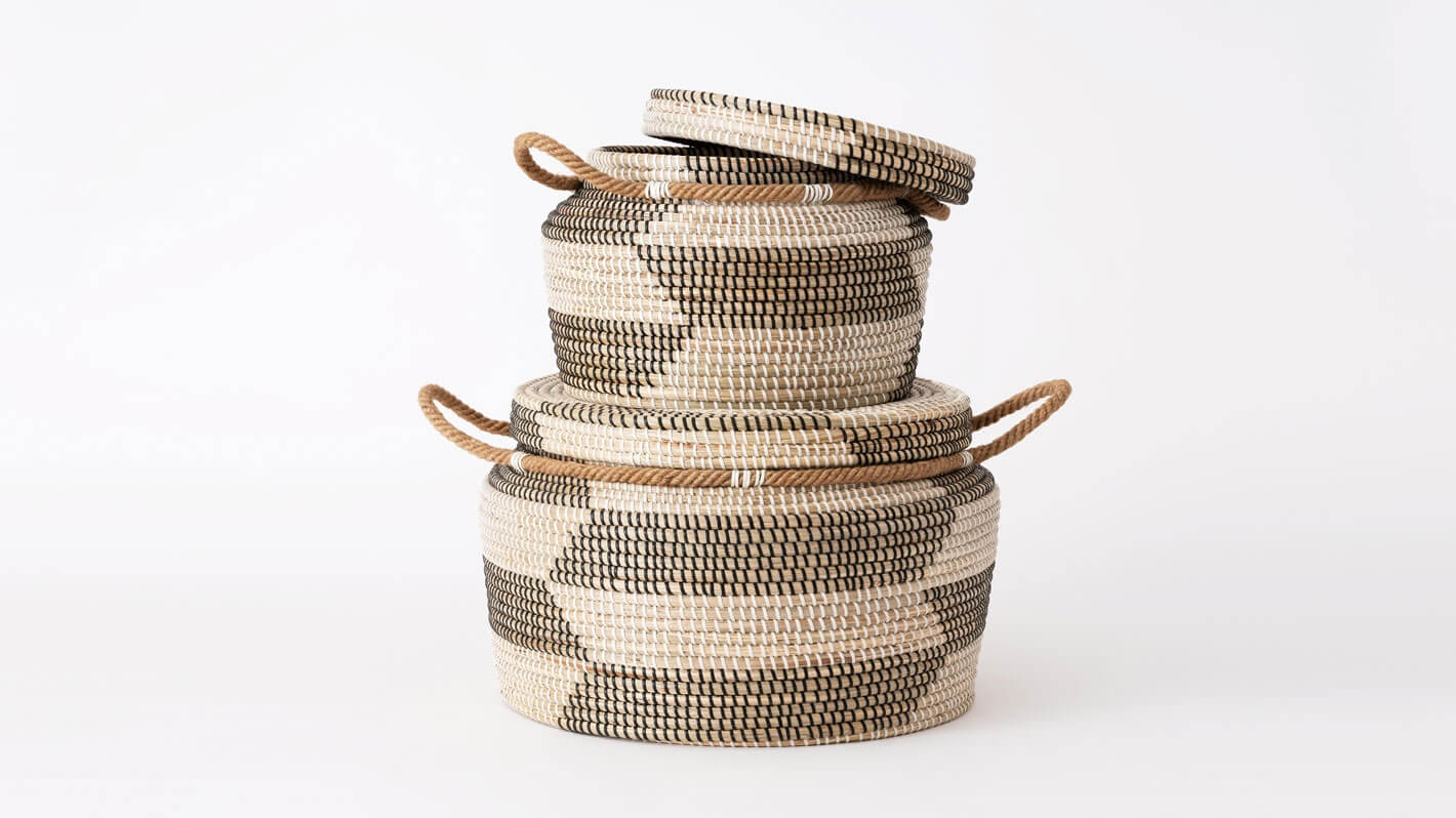 Side view of medium and large woven black and beige basket stacked with lid off