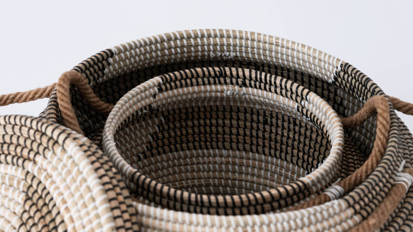 Detail view of large and medium handwoven black and beige basket stacked