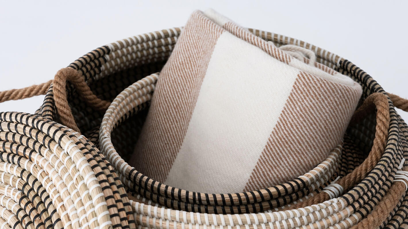 Detail view of medium and large woven black and beige basket stacked with blanket inside