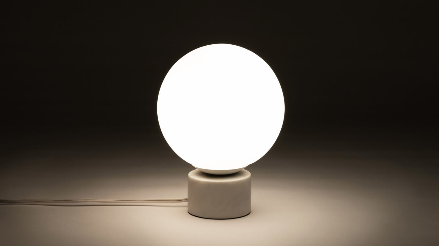 Front view of the Bassoon bedside table lamp with light on