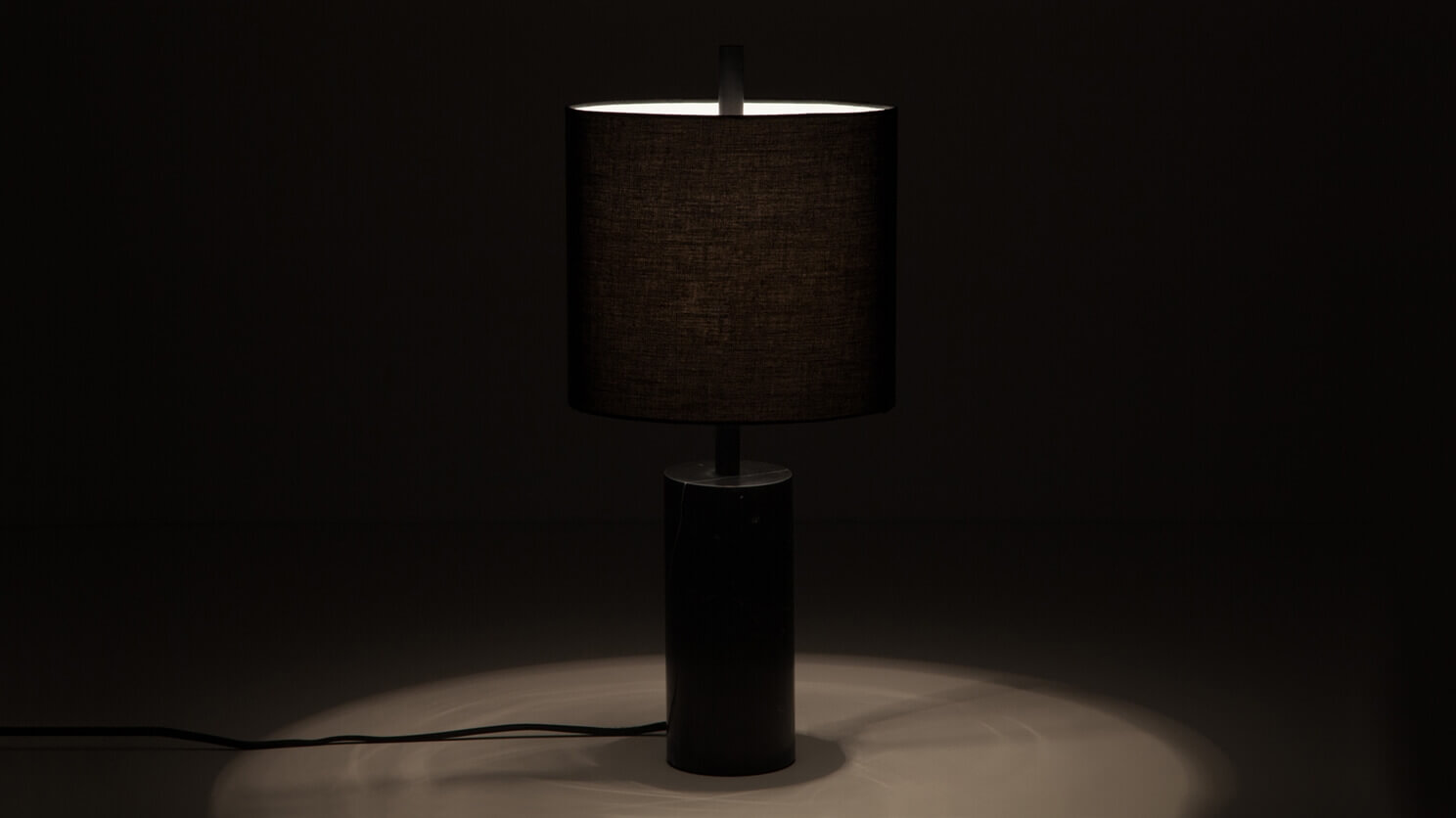 The Drum modern table lamp with black marble base with light on