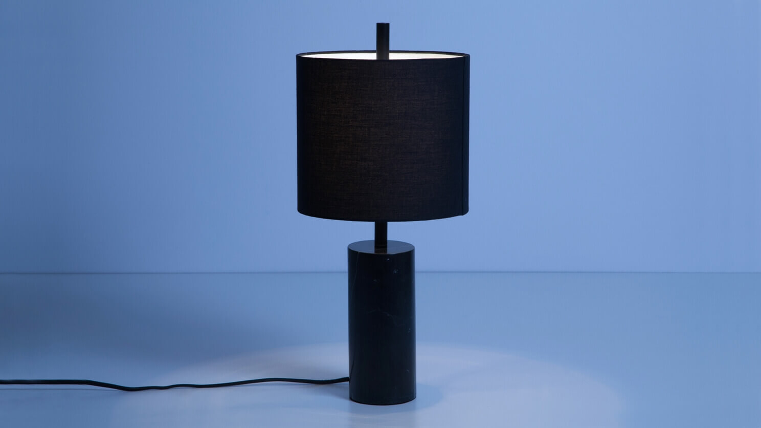 The Drum modern table lamp with black marble base in a blue room