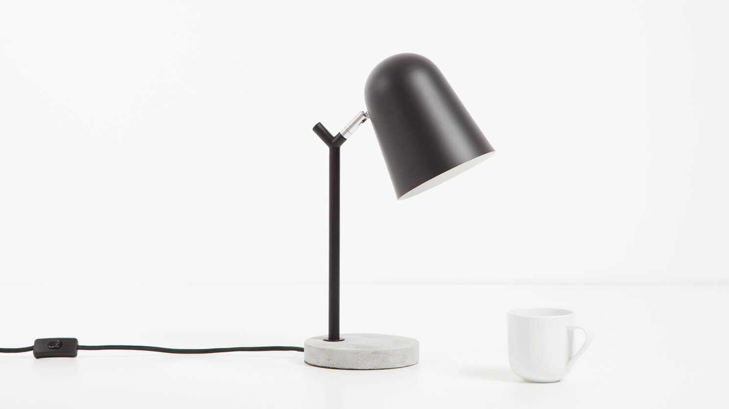 The Minor Table Lamp sits beside a white coffee mug