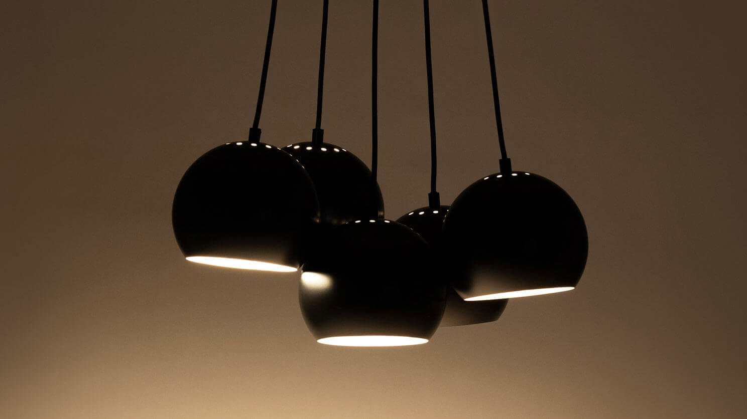 Front view of the 5 ball kitchen island pendant lighting in black with light on