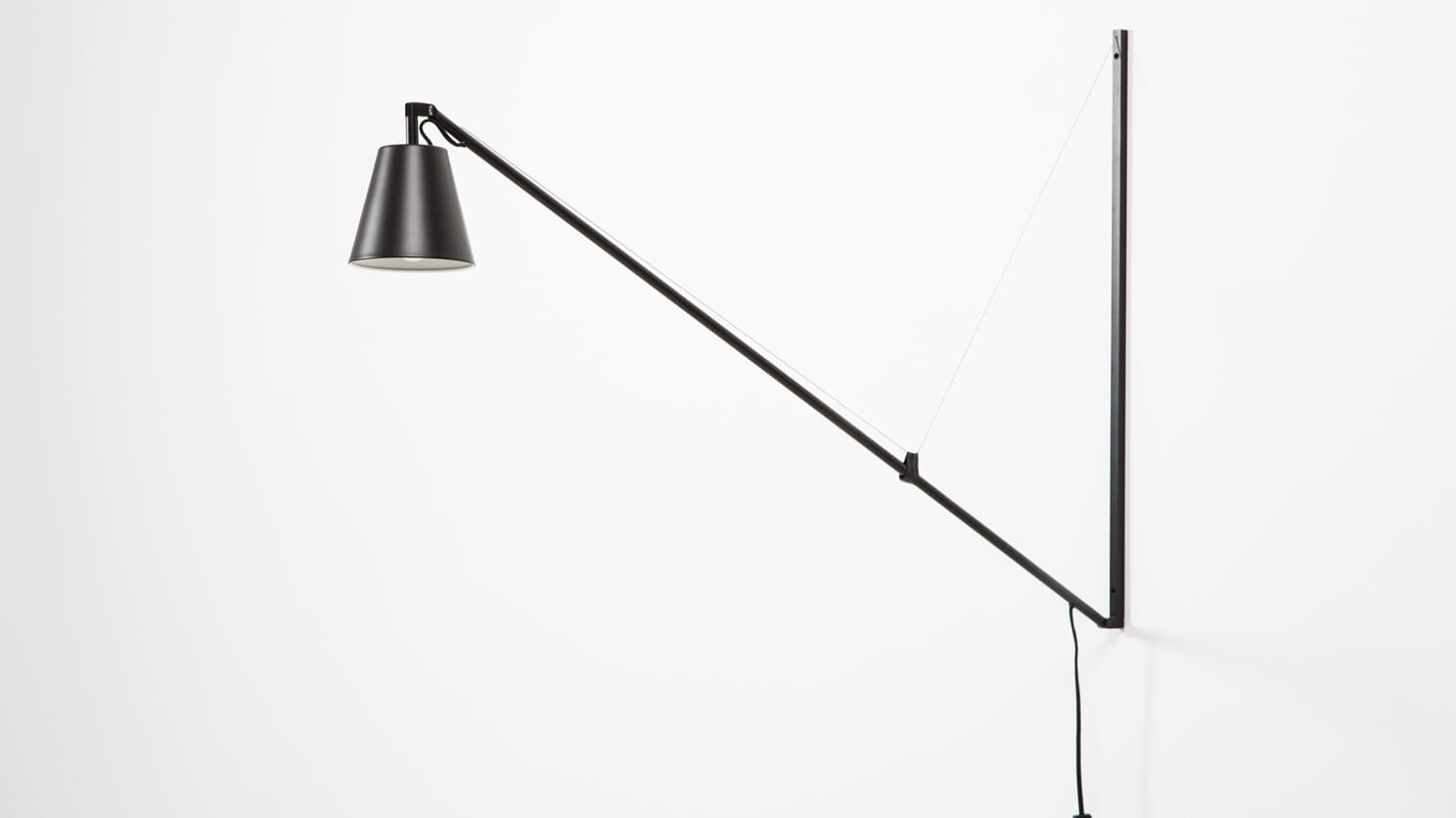 The Petrie contemporary Swing Arm Wall Lamp on a white wall angled up